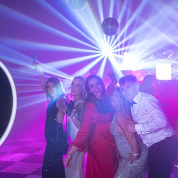 Guests posing for a roaming ring-light photo booth on a colorful dance floor