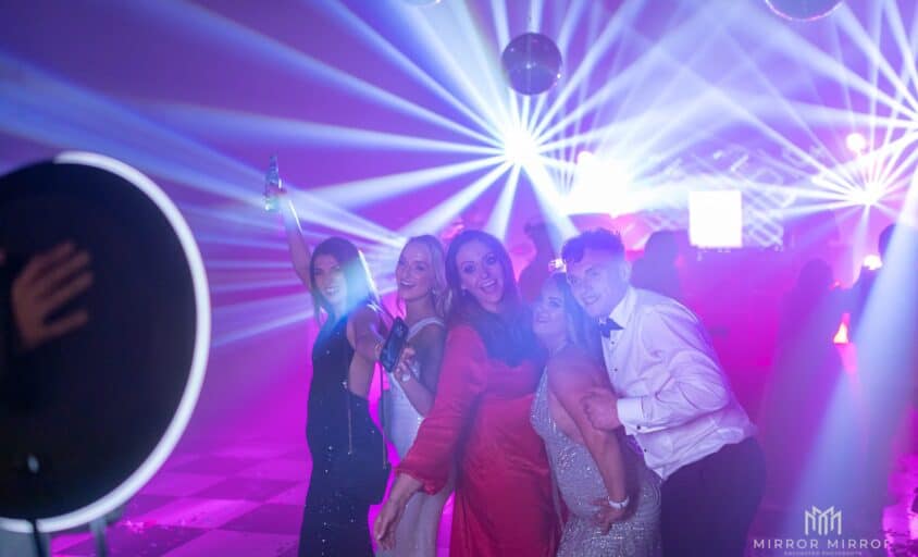 Guests posing for a roaming ring-light photo booth on a colorful dance floor