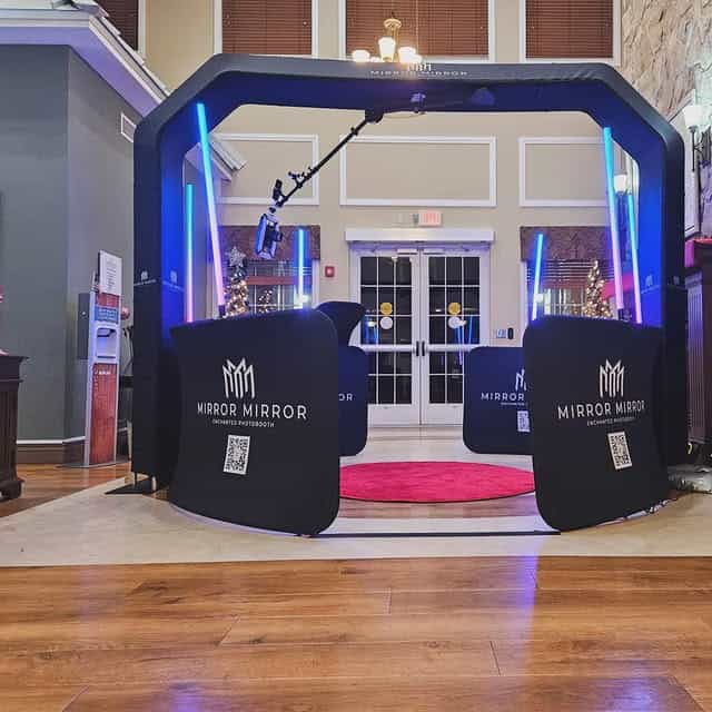 Sky 360 video booth with overhead camera, blue lighting, black barriers, and a pink floor mat at an indoor venue