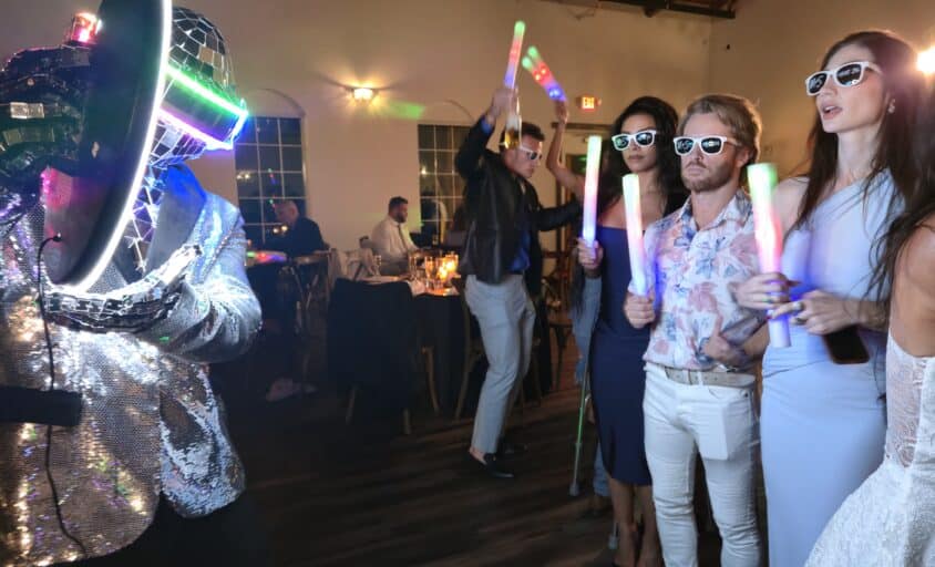 LED Robot Roamer in a mirrored light-up helmet taking a group photo with guests holding glow sticks