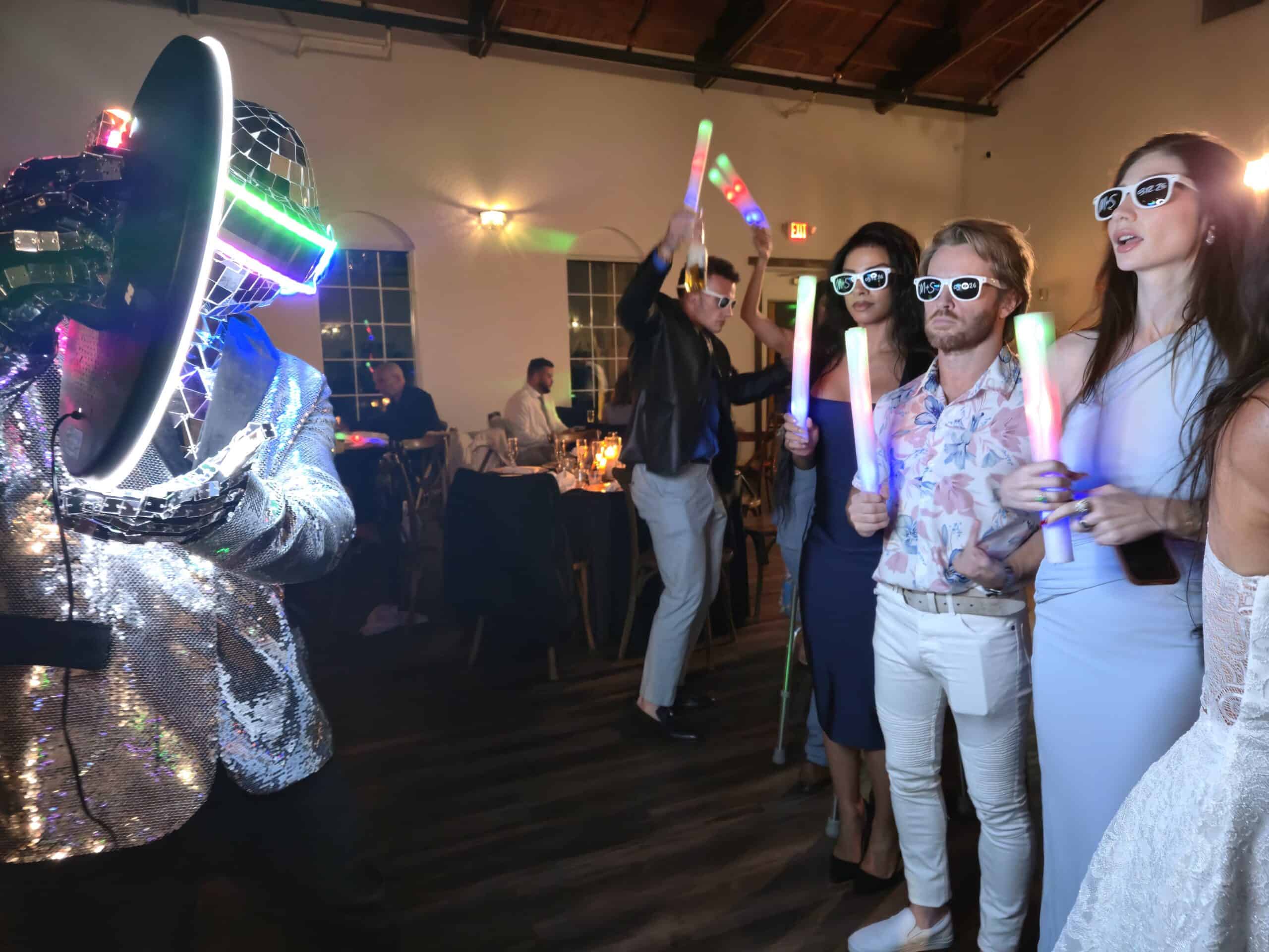 LED Robot Roamer in a mirrored light-up helmet taking a group photo with guests holding glow sticks