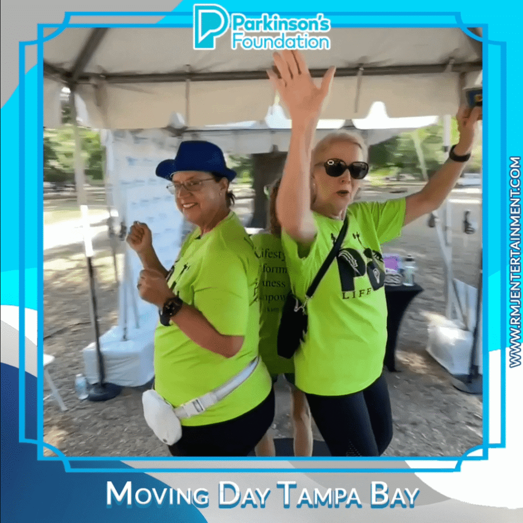 Two participants in bright green shirts enjoying the booth at Moving Day Tampa Bay