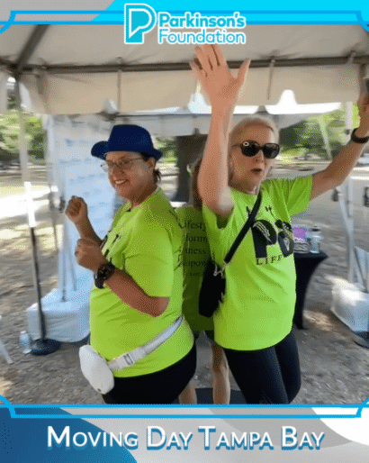Two participants in bright green shirts enjoying the booth at Moving Day Tampa Bay