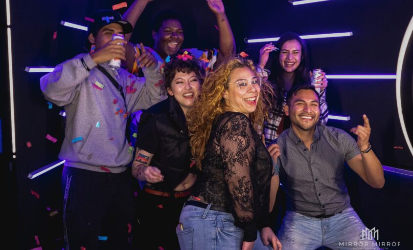 Guests celebrating inside a Vogue Booth rental with purple LED lights and confetti