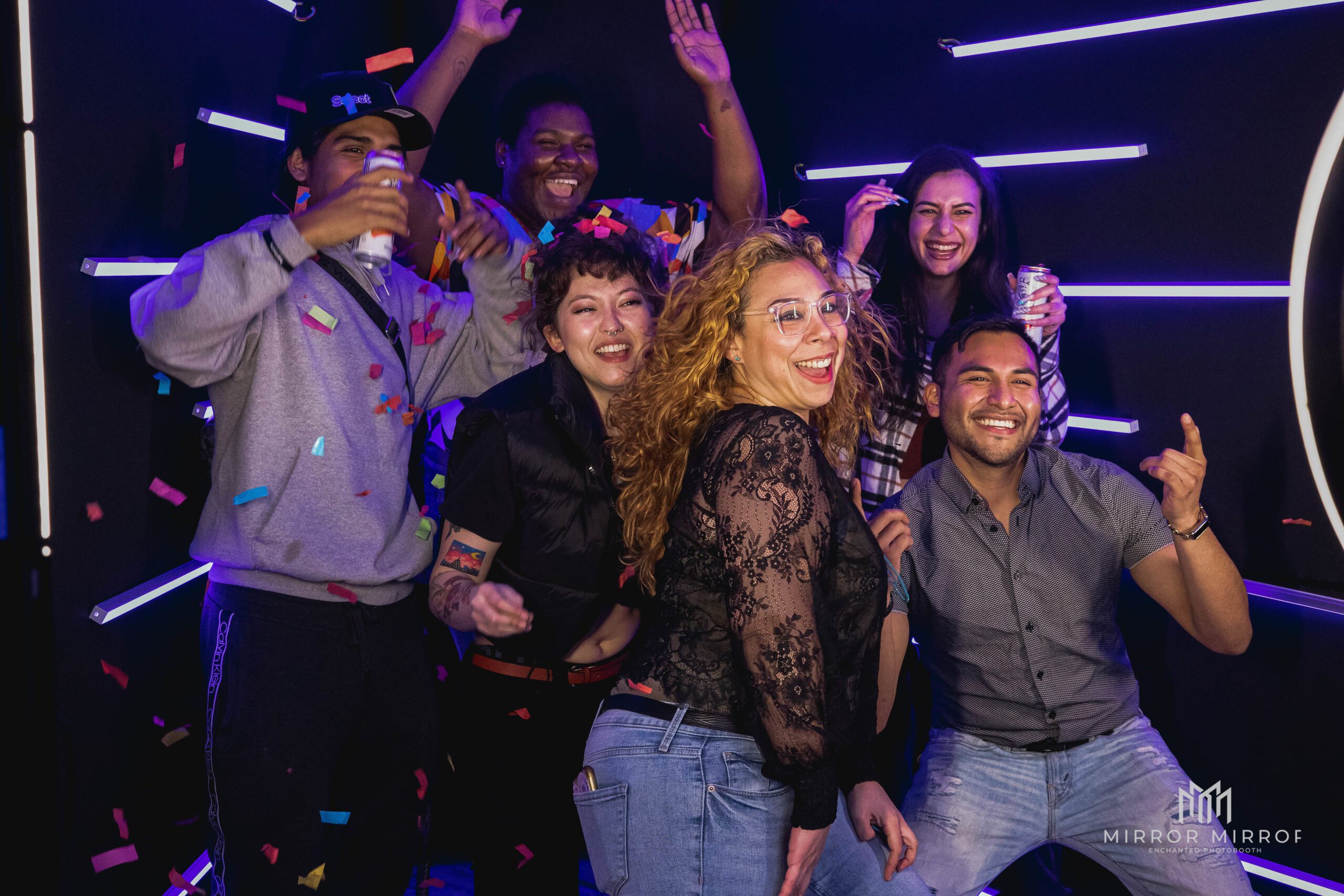 Guests celebrating inside a Vogue Booth rental with purple LED lights and confetti