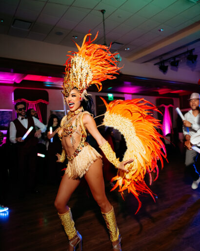 Samba dancer in an orange feathered costume entertaining guests during Hora Loca entertainment