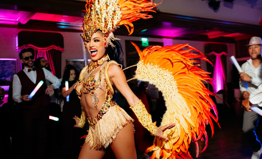 Samba dancer in an orange feathered costume entertaining guests during Hora Loca entertainment