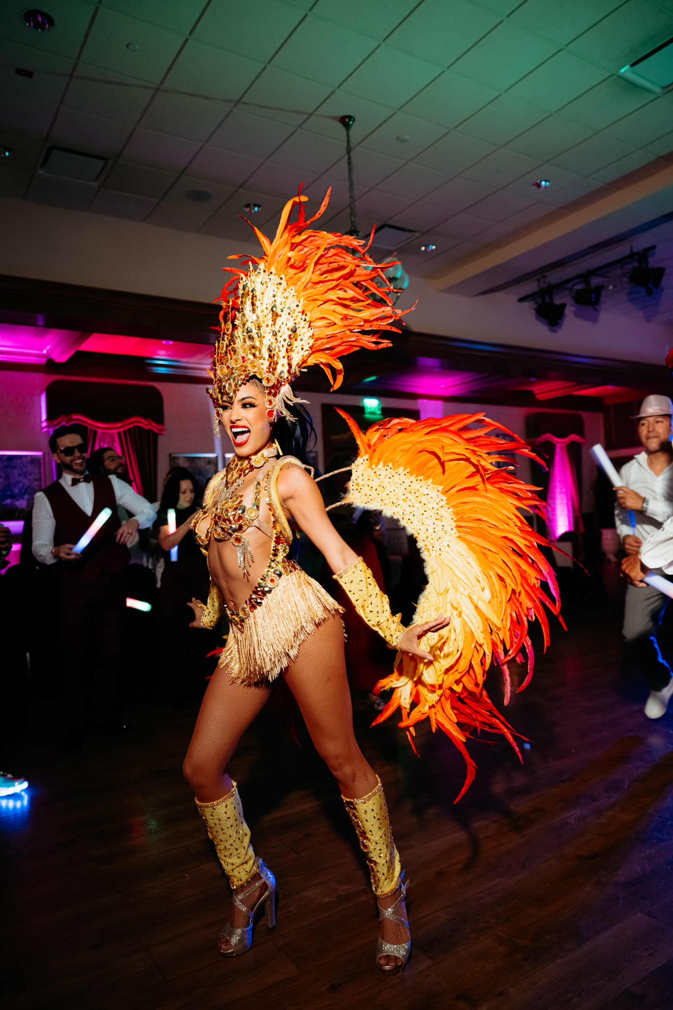 Samba dancer in an orange feathered costume entertaining guests during Hora Loca entertainment