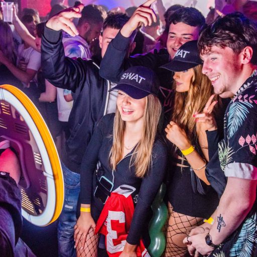 Guests posing together beside a handheld Ring Roamer photo booth at an event