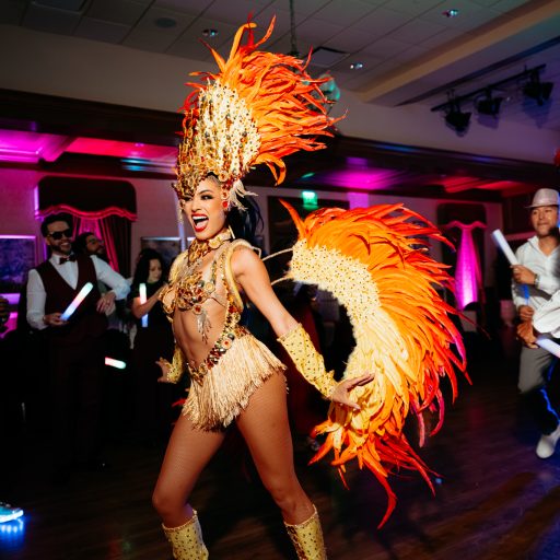 Samba dancer in an orange feathered costume entertaining guests during Hora Loca entertainment